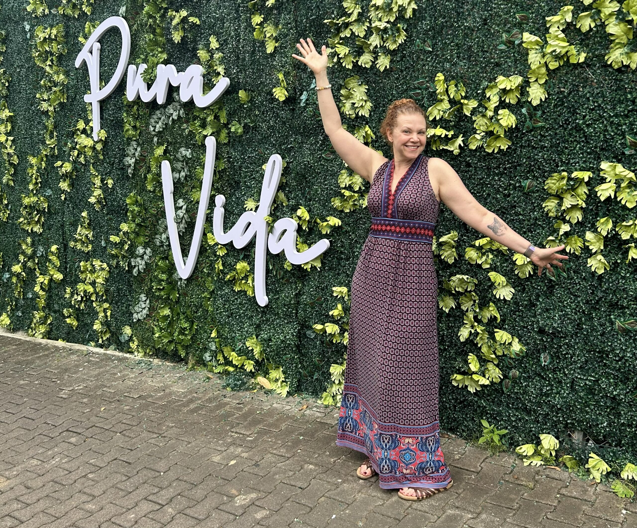 Erin Daruszka of Pause and Align smiling in front of a green Pura Vida wall